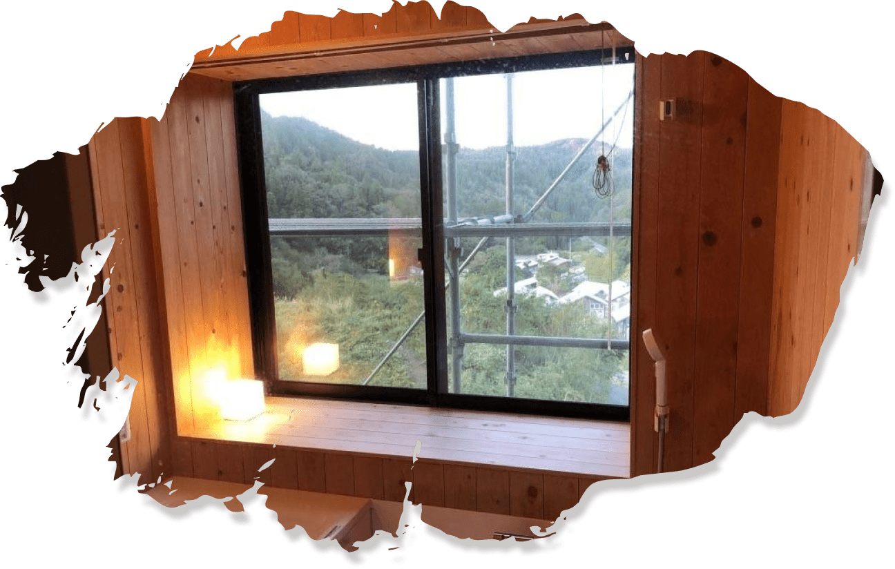 大きな窓と木の壁が特徴の浴室から見える山の景色