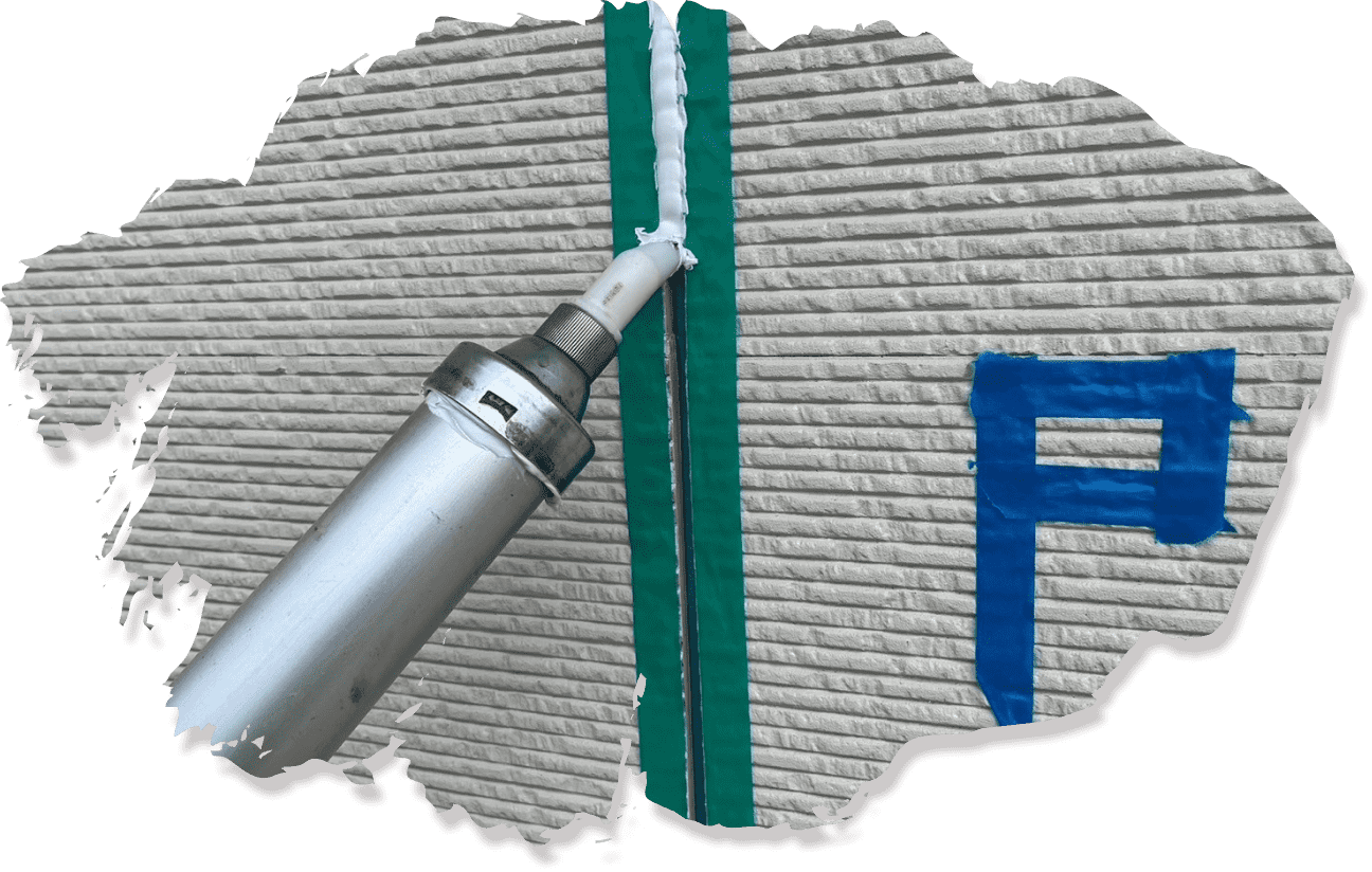 青いテープで示された目地補修が施された外壁。右側には金属製のシャッターが見える