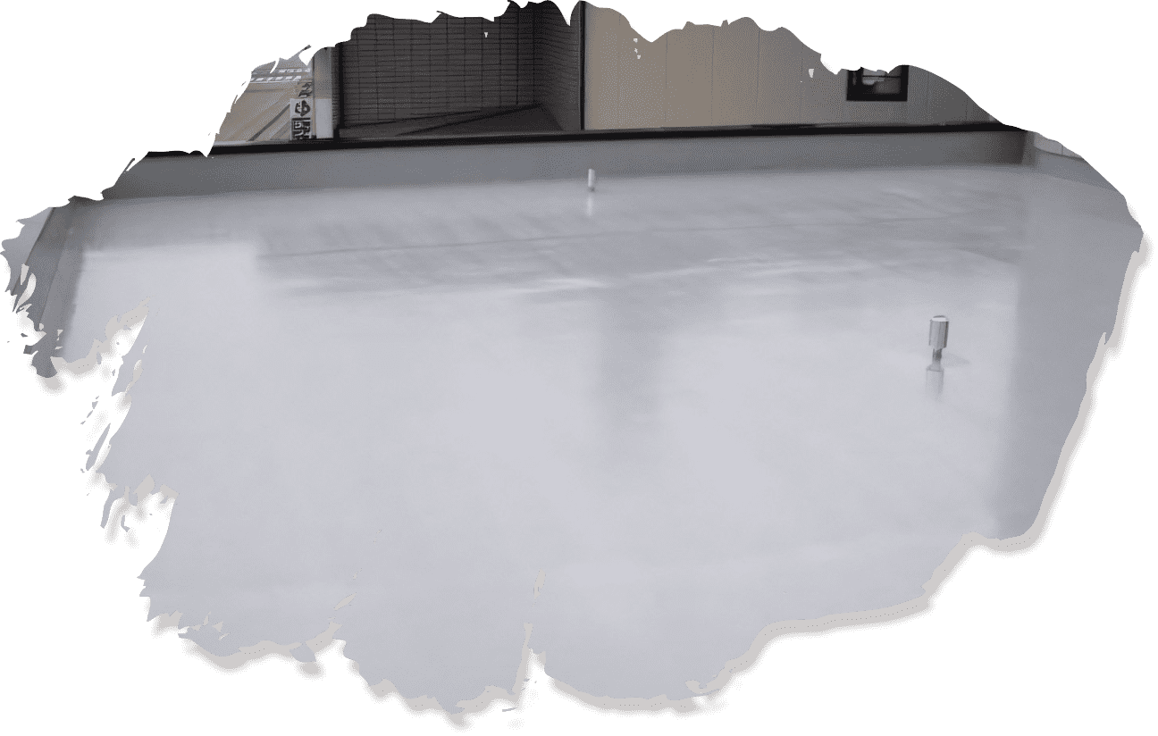 防水工事完了後の屋上で、中央に排水口が設置され、背景に壁面が映る様子